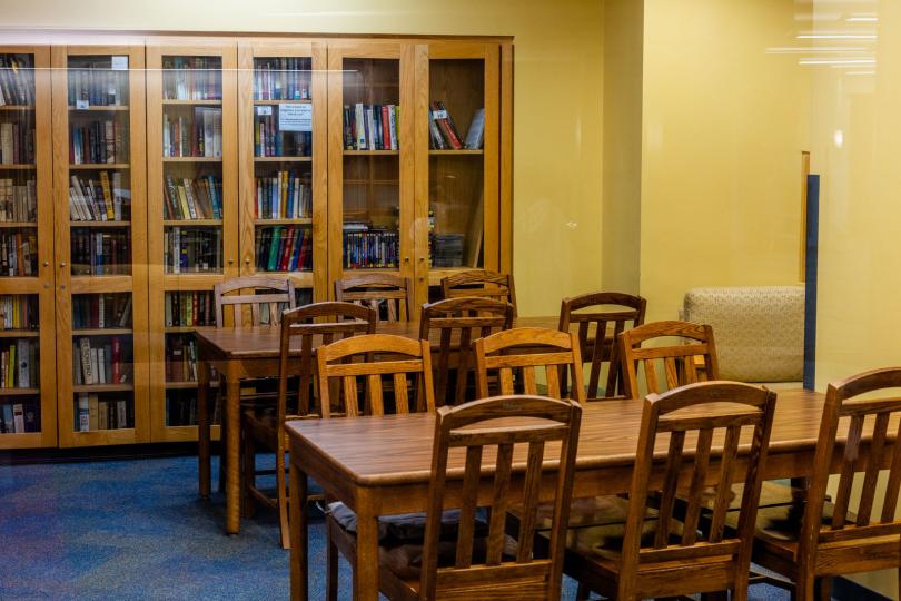 library with wooden tables and chairs as well as bookcases with books