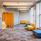 carpeted lounge with large windows and seating